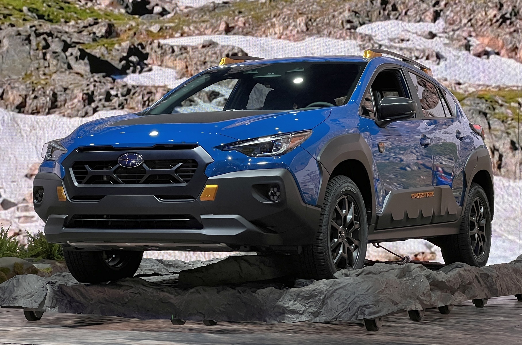 ### Subaru Crosstrek Wilderness Subaru привезла в Нью-Йорк кроссовер Crosstrek во «внедорожной» версии [Wilderness](https://motor.ru/news/subaru-crosstrek-wilderness-06-04-2023.htm) . Она получила усиленную подвеску с увеличенным на 16 миллиметров клиренсом (отличаются пружины и амортизаторы) и вездеходные шины Yokohama Geolandar. Накладки из чёрного пластика закрывают передний бампер почти целиком. Другие отличительные черты — это новая решетка радиатора в толстой рамке, увеличенные расширители колесных арок и накладки на двери и капот. Сиденья обиты водостойким материалом Subaru StarTex.