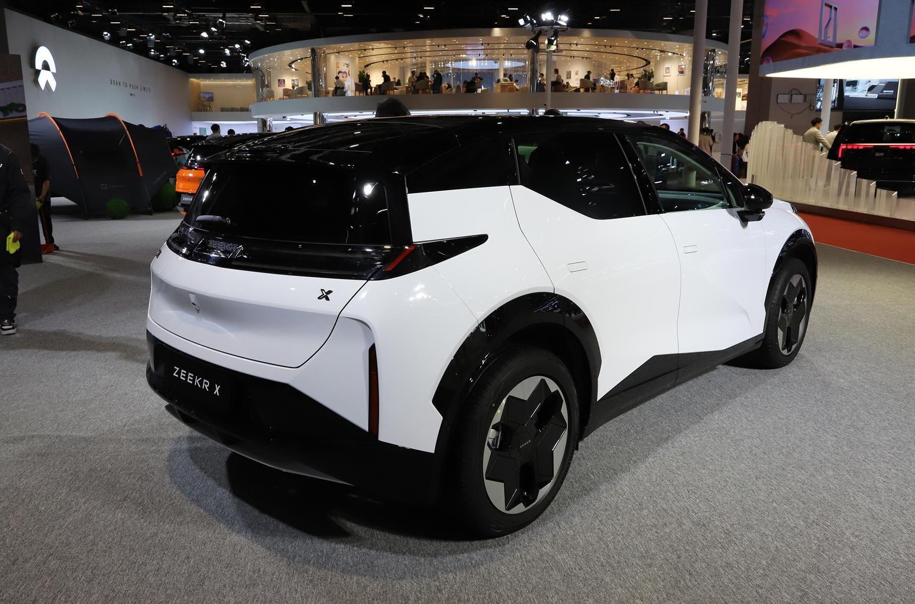 Дизайн создавался в шведской студии Geely под руководством Штефана Зилаффа, и получился куда оригинальнее большинства аналогов. Обратите внимание на ребро, пересекающее всю боковину по диагонали, на отсутствие дверных ручек (вместо них кнопки на стойках), на заднее стекло — оно состоит из двух половинок и залезает на крышу. Внутри — обычный минимализм: черно-белые оттенки, овальный двухспицевый руль, маленький виртуальный щиток приборов, ровный пол. Но с интересными нюансами: центральный экран можно передвигать по направляющим почти по всей ширине передней панели.